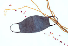 Load image into Gallery viewer, Denim blue face mask with black elastic earloops on a white background with decorative branches and rose petals scattered.