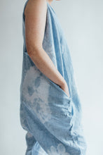 Load image into Gallery viewer, side view of model wearing indigo tie dyed jumpsuit. She is facing to the right with hand in side pocket
